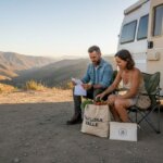 Un grupo de viajeros prepara la comida al lado de su furgoneta camper.