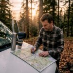 Hombre organizando su ruta en caravana al aire libre, usando un mapa