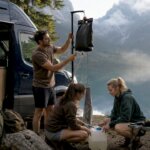 Un grupo de amigos monta una ducha portátil en su furgoneta camper