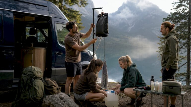 Un grupo de amigos monta una ducha portátil en su furgoneta camper
