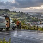 Camper y viajeros en un mirador de Chiloé con palafitos y paisaje costero