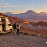 Camper y viajeros frente a volcanes y formaciones rocosas del desierto de Atacama